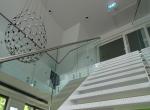 Witte stalen trap met glasbalustrade met inox handgreep