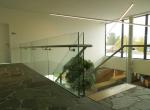 Gepoederlakte trap met treden in eik en een trapleuning-balustrade in glas met inox handgreep