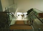 Gepoederlakte trap met treden in eik en een trapleuning-balustrade in glas met inox handgreep