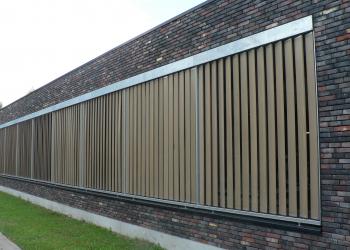 Automatische zonnewering met verticaal geplaatste houten lamellen in een metalen structuur.